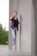 Girl ballerina in jeans, a plaid shirt and pointe shoes dancing in the city on the street © Tatiana