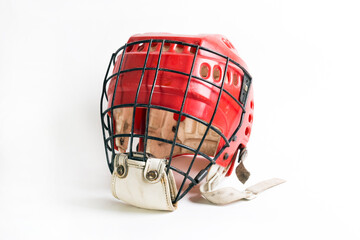 An old hockey helmet of red color with a protective iron mask on a white background