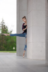 Girl ballerina in jeans, a plaid shirt and pointe shoes dancing in the city on the street © Tatiana