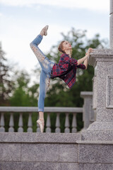 Girl ballerina in jeans, a plaid shirt and pointe shoes dancing in the city on the street © Tatiana