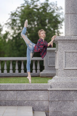 Girl ballerina in jeans, a plaid shirt and pointe shoes dancing in the city on the street © Tatiana