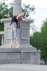 Girl ballerina in jeans, a plaid shirt and pointe shoes dancing in the city on the street © Tatiana