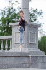 Girl ballerina in jeans, a plaid shirt and pointe shoes dancing in the city on the street © Tatiana