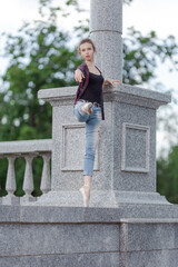 Girl ballerina in jeans, a plaid shirt and pointe shoes dancing in the city on the street © Tatiana