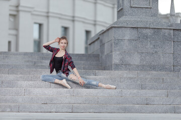 Girl ballerina in jeans, a plaid shirt and pointe shoes dancing in the city on the street © Tatiana