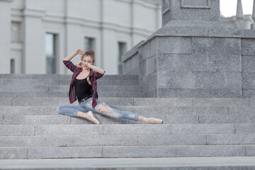 Girl ballerina in jeans, a plaid shirt and pointe shoes dancing in the city on the street © Tatiana