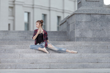Girl ballerina in jeans, a plaid shirt and pointe shoes dancing in the city on the street © Tatiana