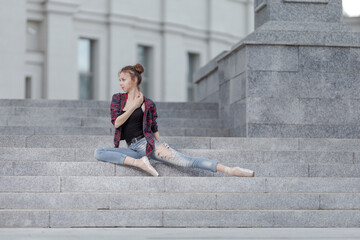 Girl ballerina in jeans, a plaid shirt and pointe shoes dancing in the city on the street © Tatiana