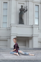 Girl ballerina in jeans, a plaid shirt and pointe shoes dancing in the city on the street © Tatiana