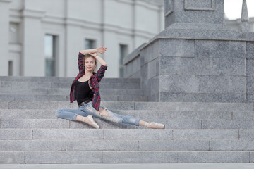 Girl ballerina in jeans, a plaid shirt and pointe shoes dancing in the city on the street © Tatiana