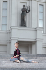 Girl ballerina in jeans, a plaid shirt and pointe shoes dancing in the city on the street © Tatiana