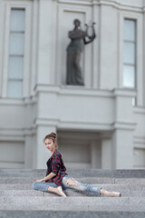 Girl ballerina in jeans, a plaid shirt and pointe shoes dancing in the city on the street © Tatiana