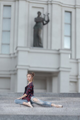 Girl ballerina in jeans, a plaid shirt and pointe shoes dancing in the city on the street © Tatiana