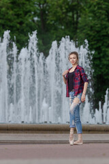 Girl ballerina in jeans, a plaid shirt and pointe shoes dancing in the city on the street © Tatiana