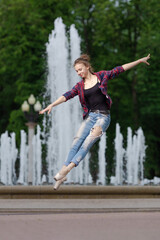 Girl ballerina in jeans, a plaid shirt and pointe shoes dancing in the city on the street © Tatiana