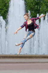 Girl ballerina in jeans, a plaid shirt and pointe shoes dancing in the city on the street © Tatiana