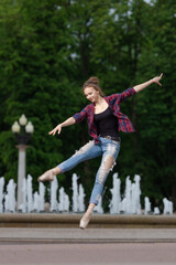 Girl ballerina in jeans, a plaid shirt and pointe shoes dancing in the city on the street © Tatiana