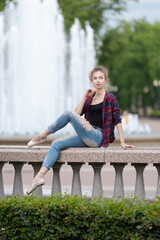 Girl ballerina in jeans, a plaid shirt and pointe shoes dancing in the city on the street © Tatiana