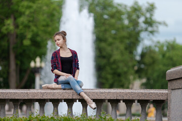 Girl ballerina in jeans, a plaid shirt and pointe shoes dancing in the city on the street © Tatiana