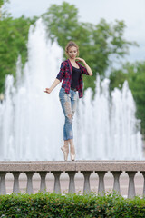 Girl ballerina in jeans, a plaid shirt and pointe shoes dancing in the city on the street © Tatiana