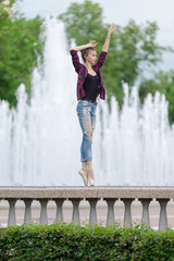 Girl ballerina in jeans, a plaid shirt and pointe shoes dancing in the city on the street © Tatiana