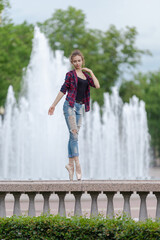 Girl ballerina in jeans, a plaid shirt and pointe shoes dancing in the city on the street © Tatiana