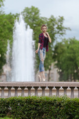 Girl ballerina in jeans, a plaid shirt and pointe shoes dancing in the city on the street © Tatiana