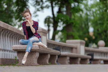 Girl ballerina in jeans, a plaid shirt and pointe shoes dancing in the city on the street © Tatiana