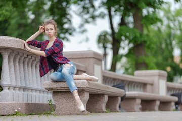 Girl ballerina in jeans, a plaid shirt and pointe shoes dancing in the city on the street © Tatiana