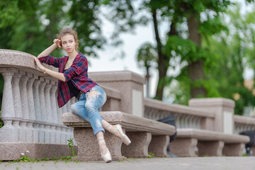 Girl ballerina in jeans, a plaid shirt and pointe shoes dancing in the city on the street © Tatiana