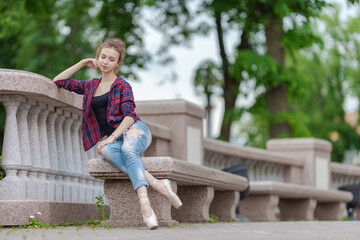 Girl ballerina in jeans, a plaid shirt and pointe shoes dancing in the city on the street © Tatiana