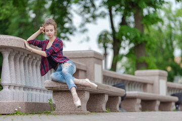 Girl ballerina in jeans, a plaid shirt and pointe shoes dancing in the city on the street © Tatiana