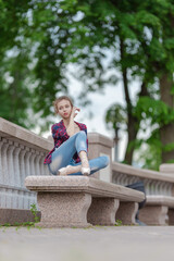 Girl ballerina in jeans, a plaid shirt and pointe shoes dancing in the city on the street © Tatiana