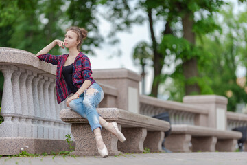Girl ballerina in jeans, a plaid shirt and pointe shoes dancing in the city on the street © Tatiana