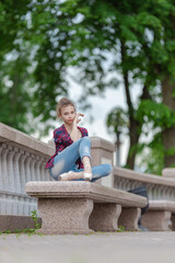 Girl ballerina in jeans, a plaid shirt and pointe shoes dancing in the city on the street © Tatiana
