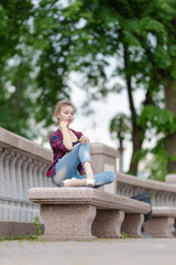 Girl ballerina in jeans, a plaid shirt and pointe shoes dancing in the city on the street © Tatiana