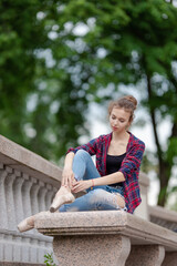 Girl ballerina in jeans, a plaid shirt and pointe shoes dancing in the city on the street © Tatiana