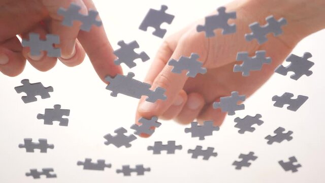 Assembling jigsaw puzzle. Pieces of a jigsaw puzzle interconnecting by male hand. Fast learning concept. Finding solution for business. Part of the whole. Assigning to learn a segment
