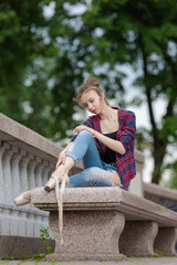 Girl ballerina in jeans, a plaid shirt and pointe shoes dancing in the city on the street © Tatiana
