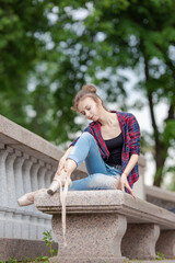 Girl ballerina in jeans, a plaid shirt and pointe shoes dancing in the city on the street © Tatiana