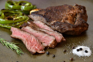 Close up Sliced medium rare grilled steak with salt,Bell pepper and rosemary placed on plate.