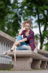 Girl ballerina in jeans, a plaid shirt and pointe shoes dancing in the city on the street © Tatiana