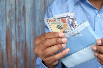 Close up of man saving cash in wallet 