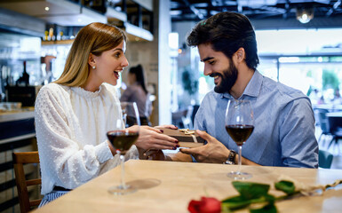 Birthday present for a girlfriend. Romantic couple sitting in the cafe and drinking red wine. Dating, love, relationships
