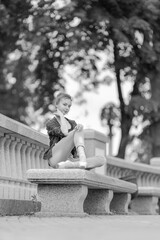 Black and white photo of a ballerina girl in jeans and pointe shoes, dancing and posing in the city on the street © Tatiana