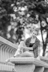 Black and white photo of a ballerina girl in jeans and pointe shoes, dancing and posing in the city on the street © Tatiana