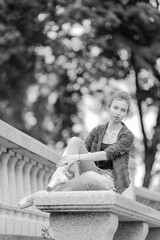 Black and white photo of a ballerina girl in jeans and pointe shoes, dancing and posing in the city on the street © Tatiana