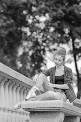 Black and white photo of a ballerina girl in jeans and pointe shoes, dancing and posing in the city on the street © Tatiana