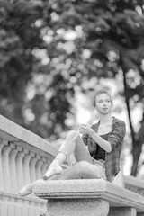 Black and white photo of a ballerina girl in jeans and pointe shoes, dancing and posing in the city on the street © Tatiana