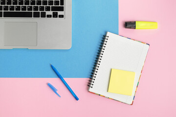 Notebook, copybook, pen and highlighter on blue and pink background.